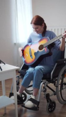 Genç engelli bir bayan gitardan bahsediyor ve çalmaya hazırlanıyor.