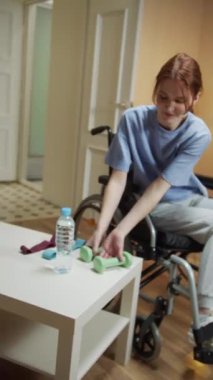 Engelli bir kadın dambıllarla el egzersizi yapıyor. 