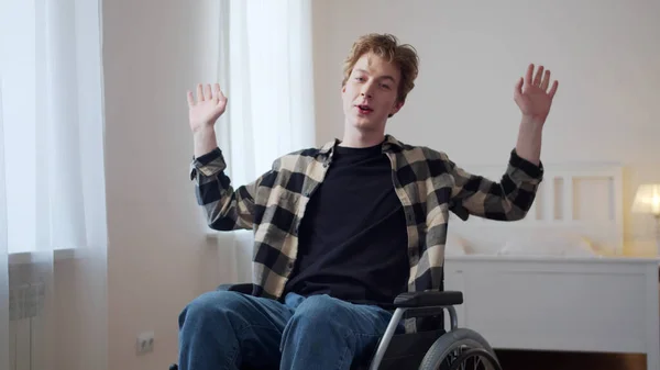 Un joven está sentado en una silla de ruedas y hablando con la cámara — Foto de Stock