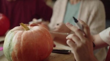 Yaşlı bir adam ve bir kadın dikkatle izliyorlar bir usta bir balkabağını kalemle çizerken