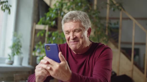 Grandpa speaks with family via video call. He talks and smiles cheerfully — Stock Video