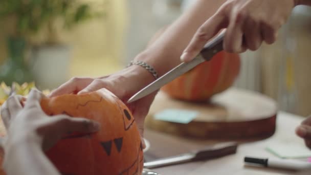Close up, amigos se preparando para o dia das bruxas e cortar os olhos de abóbora com uma faca afiada — Vídeo de Stock