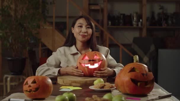 Flicka sitter vid middagsbordet och håller en pumpa för halloween — Stockvideo