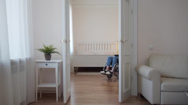 Een jonge gehandicapte vrouw rijdt in haar rolstoel door de kamer — Stockvideo