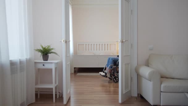 Una joven discapacitada está montando en su silla de ruedas alrededor de la habitación — Vídeo de stock