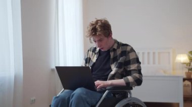 Engelli bir adam tekerlekli sandalyesinde oturuyor ve internete bakıyor. 