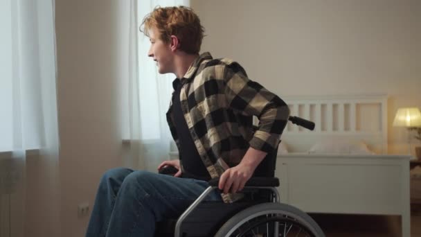 Людина з обмеженими можливостями їде на інвалідному візку через кімнату — стокове відео