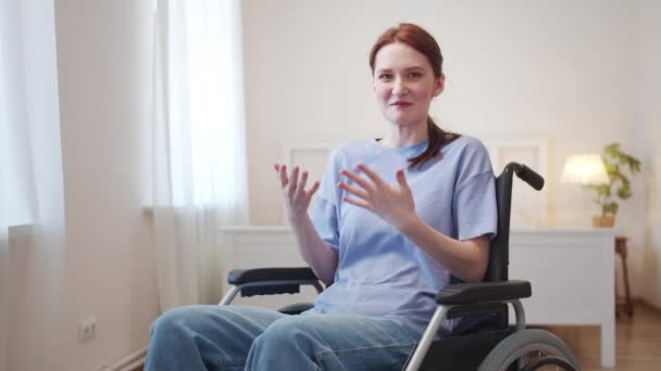 Een jonge vrouw zit in een rolstoel en praat met de camera. — Stockvideo