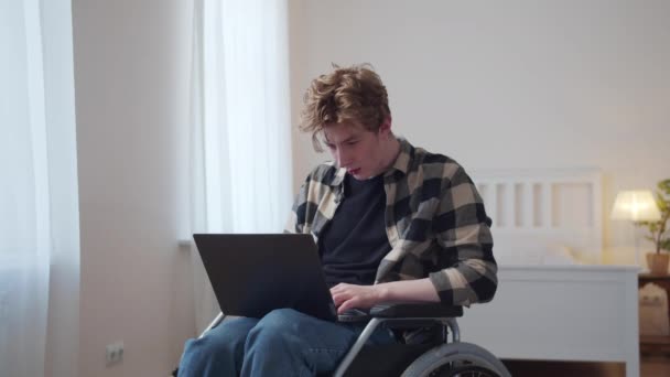 Een gehandicapte man zit in zijn rolstoel en kijkt door het internet — Stockvideo