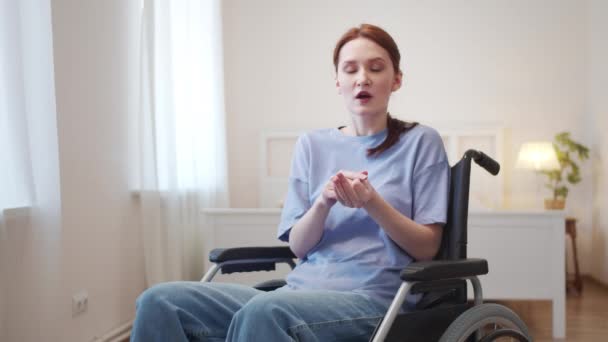 Seorang wanita muda duduk di kursi roda dan berbicara dengan kamera — Stok Video