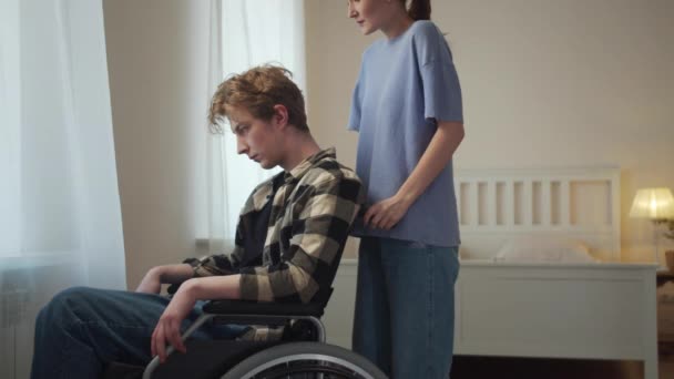 Una donna sta guidando il suo ragazzo su una sedia a rotelle — Video Stock