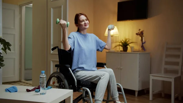 A disabled woman is making hand exercises with dumbbells — Stock Photo, Image