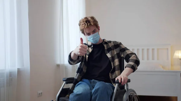 En ung handicappet mand tager en maske på. Stock-billede