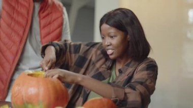 Kadın balkabağını bıçakla keser, gülümser ve güler.