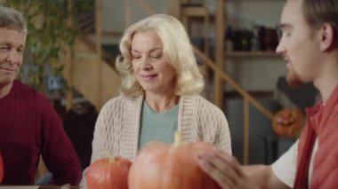 Bir adam sevdiklerine Cadılar Bayramı 'nda nasıl balkabağı çizileceğini açıklar. Yaşlı bir çift ve bir öğrenci ustayı dikkatle dinleyin.