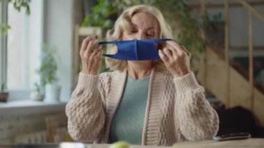 Yaşlanan bir kadın tıbbi maskesini çıkarır. Sakince nefes verir ve gülümser.