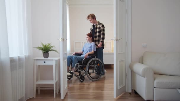 Un homme conduit sa petite amie dans un fauteuil roulant — Video