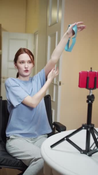 Uma mulher esportiva deficiente está mostrando um exercício com elástico esportivo em um vídeo — Vídeo de Stock