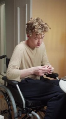 Özürlü bir genç adam dikkatle bir film izliyor.