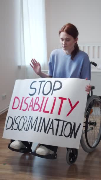 A disabled attractive woman is showing a poster and looking to the camera — Stock Video