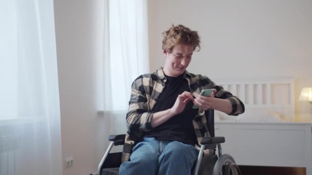 Seorang pria cacat duduk di kursi rodanya dan melihat melalui internet — Stok Video