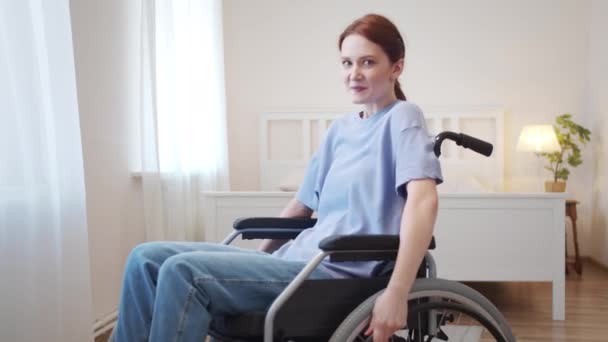 Seorang wanita muda duduk di kursi roda dan melihat ke kamera — Stok Video