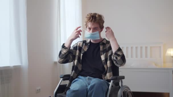 Ein junger behinderter Mann setzt sich eine Maske über das Gesicht — Stockvideo