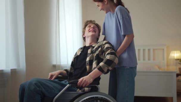 Młoda kobieta jeździ swoim przyjacielem na wózku inwalidzkim — Wideo stockowe