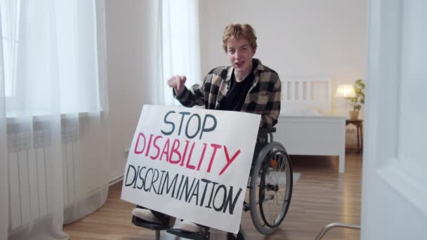 Ein Behinderter zeigt ein Plakat und blickt in die Kamera — Stockvideo