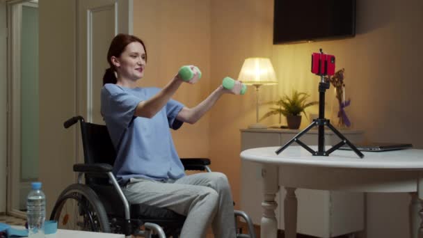 A disabled woman is making an exercise with dumbbells on the Internet — Stock Video