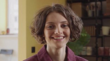 Genç ve güzel bir bayan kameraya bakıyor ve gülümsüyor.