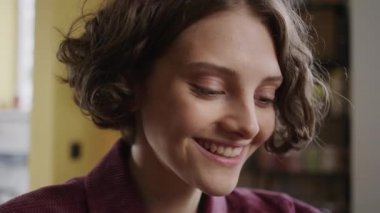 Yakışıklı bir kız bir şeye bakıyor ve gülümsüyor.