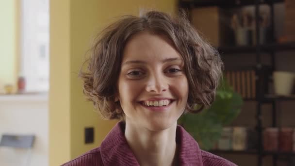 O tânără frumoasă doamnă se uită la cameră și zâmbește — Videoclip de stoc