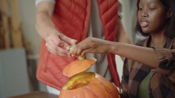 A cute young lady finishes carving a halloween pumpkin — Stock Video