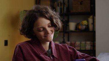 Güzel bir bayan telefonda bir şeye bakıyor ve gülümsüyor.