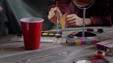 Güzel bir kız fırçayla boya topluyor.