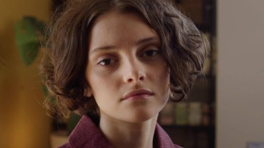 Genç ve güzel bir bayan kameraya bakıyor ve poz veriyor.