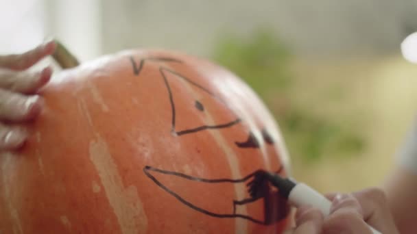 Молодий чоловік малює над ротом гарбуза крупним планом — стокове відео