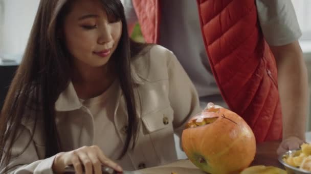 Una joven linda termina de tallar una calabaza de halloween — Vídeo de stock