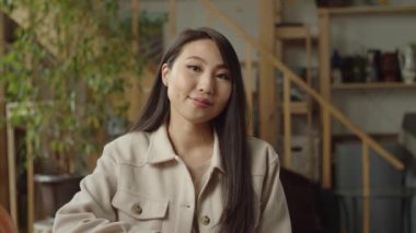 Yakışıklı bir bayan oturuyor ve kameraya bakıyor.