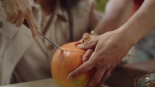 Красивий молодий чоловік допомагає своєму другу вирізати гарбуз на Хелловін — стокове відео