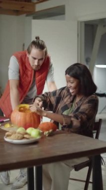 Genç bir bayan balkabağını oyuyor.