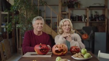 Bir oğul ve ailesi el yapımı balkabaklarıyla masada oturuyor ve kameraya bakıyor. Yüksek kalite 4k görüntü