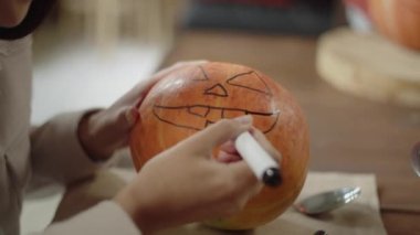 Yetişkin bir kadın cadılar bayramı balkabağına bir ahmak suratı çizmeyi bitiriyor. Yüksek kalite 4k görüntü