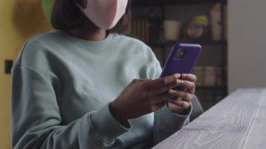 Koruyucu maskeli güzel bir bayan telefonda bir şeye bakıyor. Yüksek kalite 4k görüntü