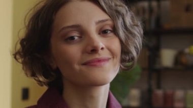 Genç ve güzel bir bayan kameraya bakıyor ve gülümsüyor. Yüksek kalite 4k görüntü