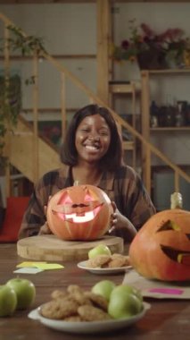 Güzel bir bayan bir balkabağı tutuyor ve kameraya bakıyor. Yüksek kaliteli FullHD görüntüler