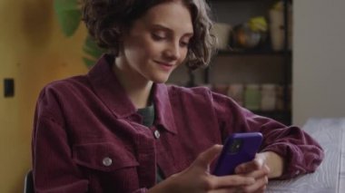 Güzel bir bayan telefonda bir şeye bakıyor ve gülümsüyor. Yüksek kalite 4k görüntü