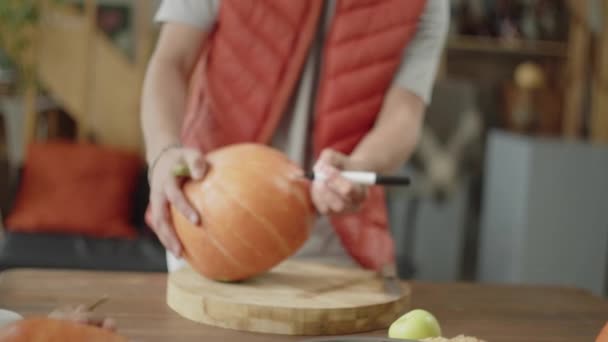An adult man is drawing a pattern on a pumpkin — Stock Video