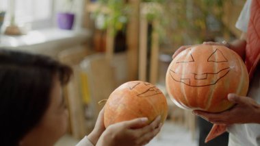 Arkadaşlar cadılar bayramı balkabaklarını karşılaştırıyor.